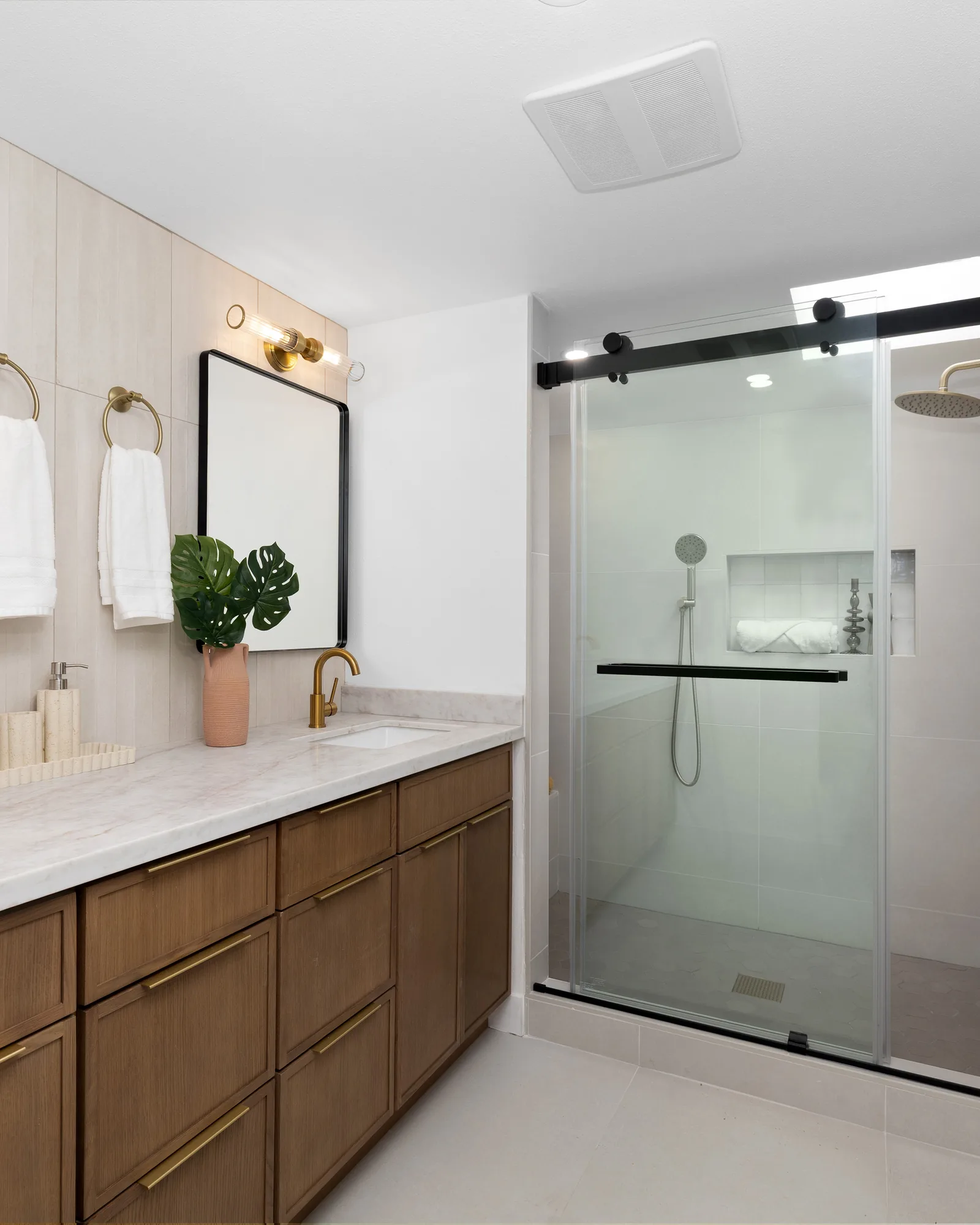 A bathroom with a double vanity in white oak and a walk-in shower